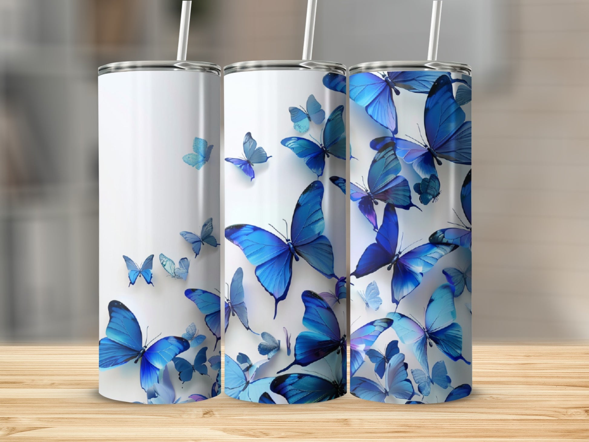 Three white tumblers with blue butterflies, displayed on a wooden surface.