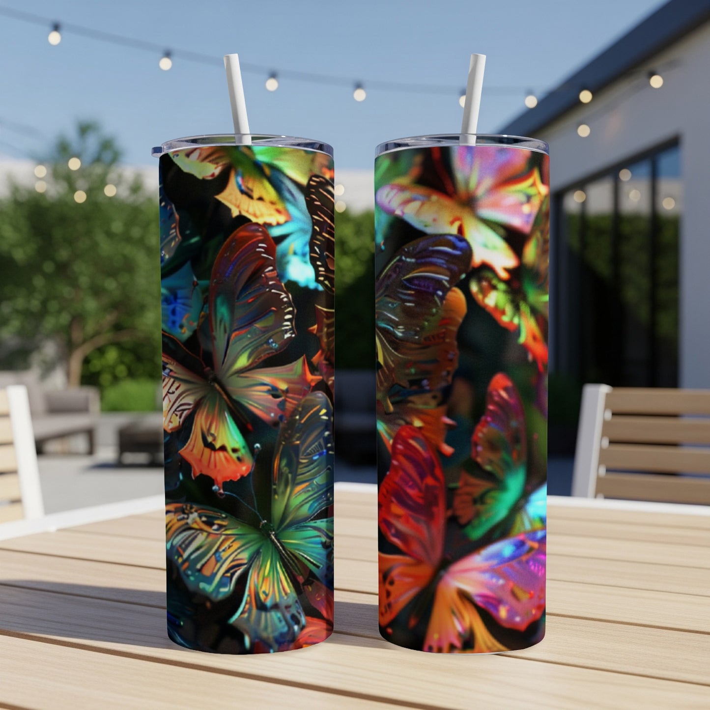 Two colorful, iridescent butterfly-patterned tumblers with straws on a wooden table.