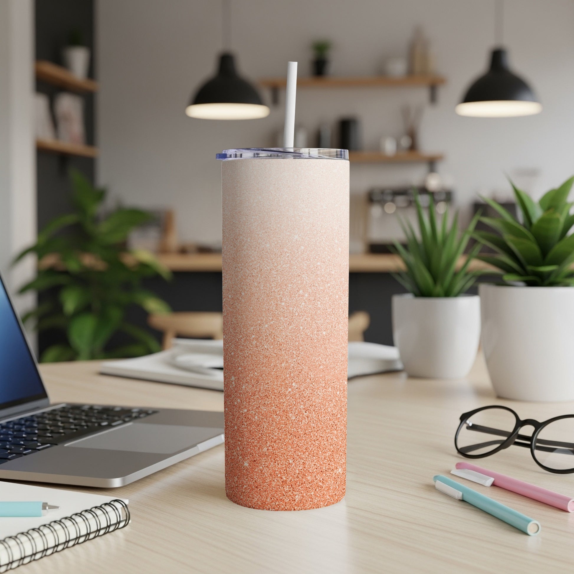 Orange glitter gradient skinny tumbler with straw on a desk.