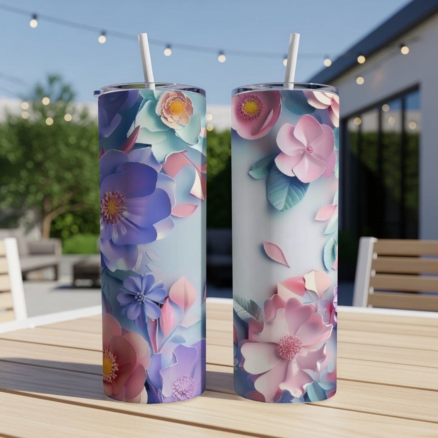 Two floral patterned tumblers with straws on a table.