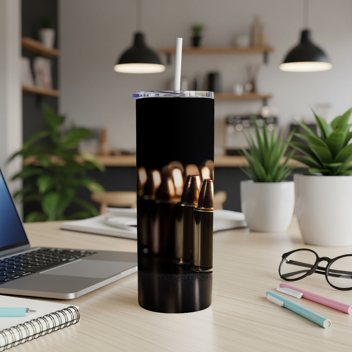 Black tumbler with a pattern of bullets on a desk next to a laptop.