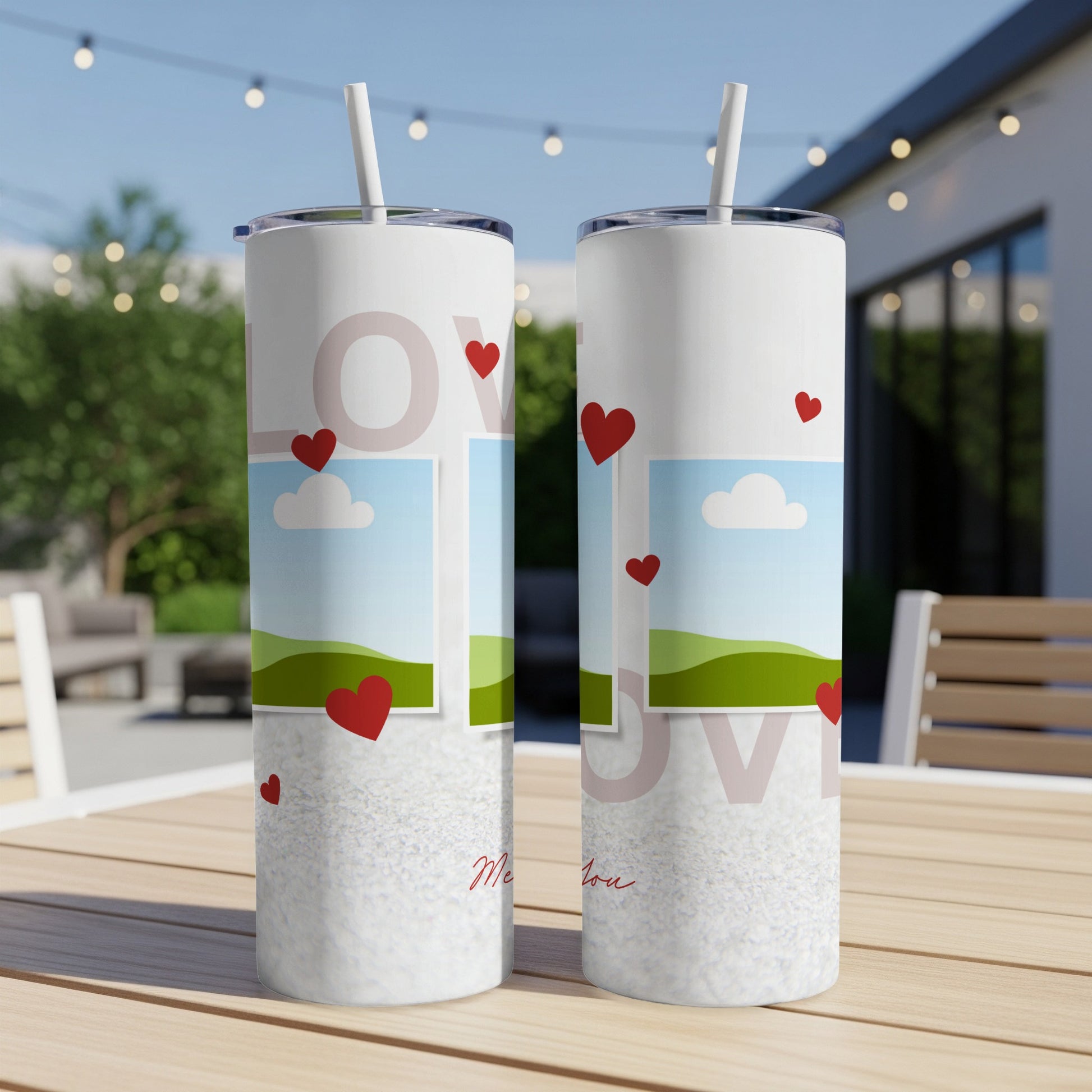 Two white tumblers with red hearts, landscapes, and "love" text on a table.