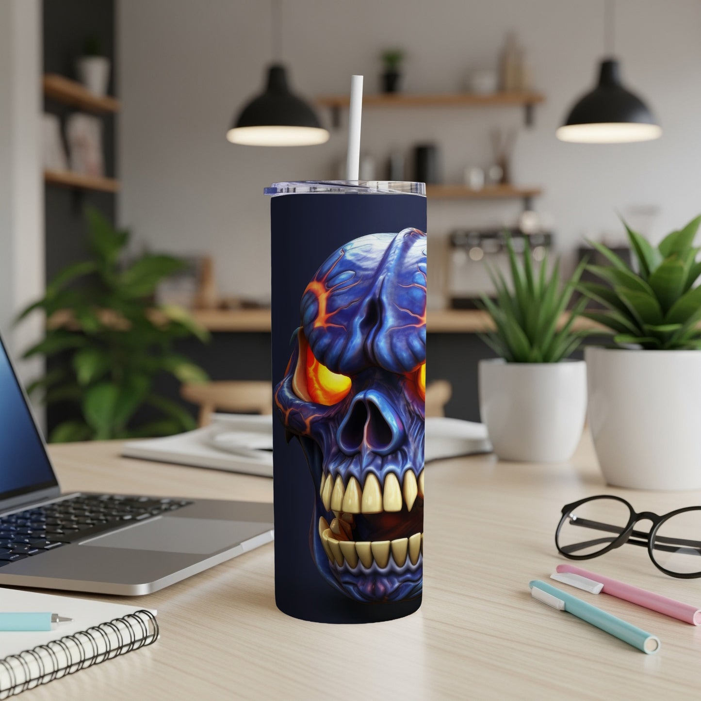 Dark blue tumbler with a detailed, fiery blue and orange skull design and a white straw.