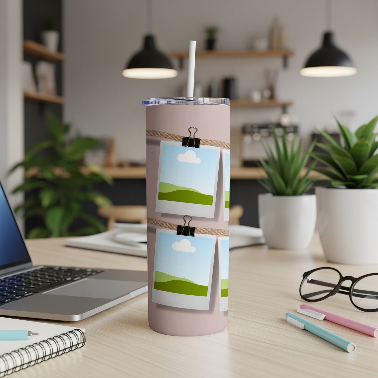 Pink tumbler with string and clothespins holding landscape photos.