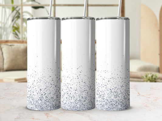 Three white glitter tumblers with straws on a marbled surface.