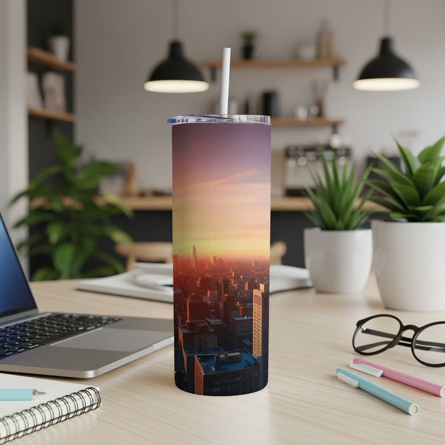 Tumbler with sunset cityscape design on a desk.