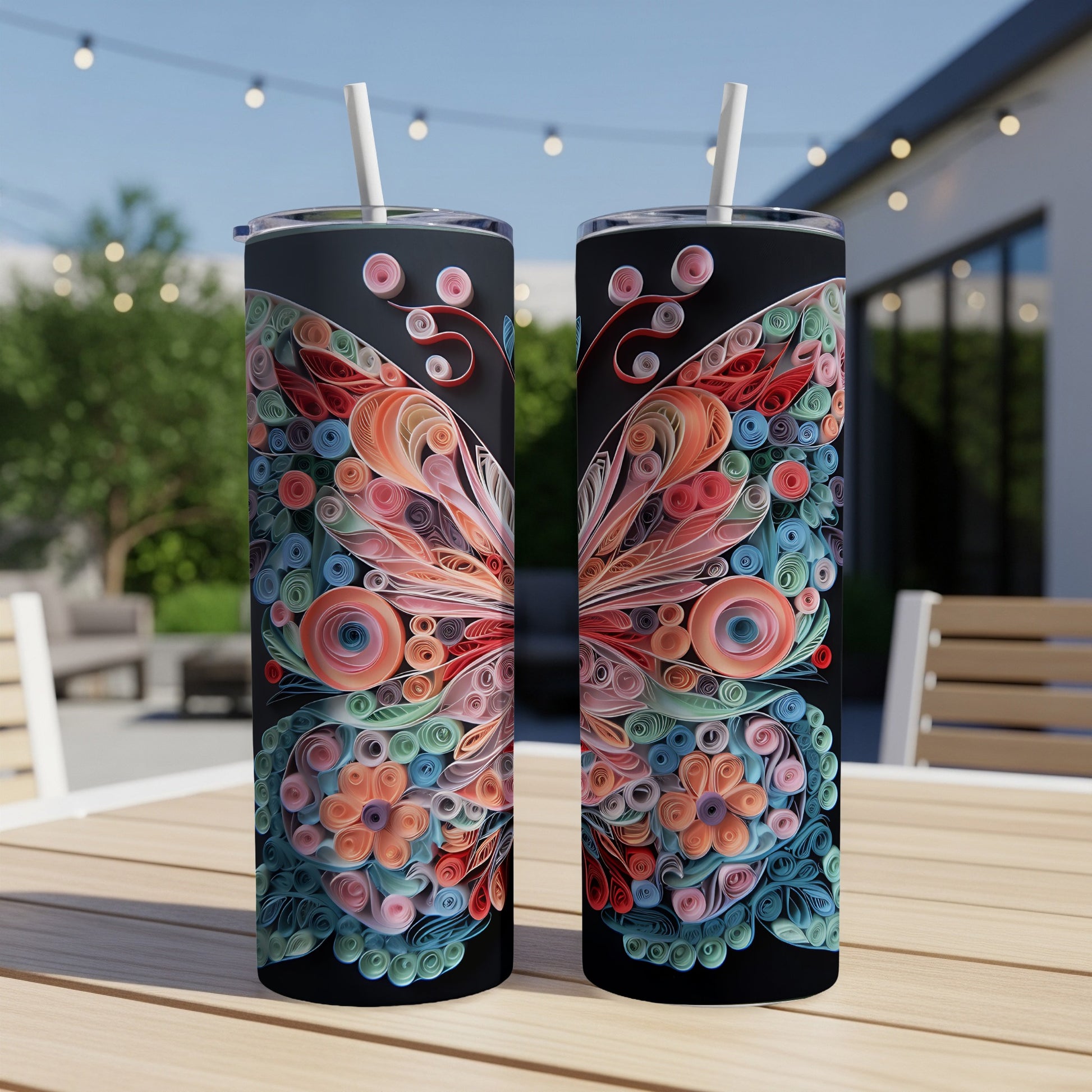 Two tumblers with colorful quilled paper butterfly designs stand on a wooden table outdoors.