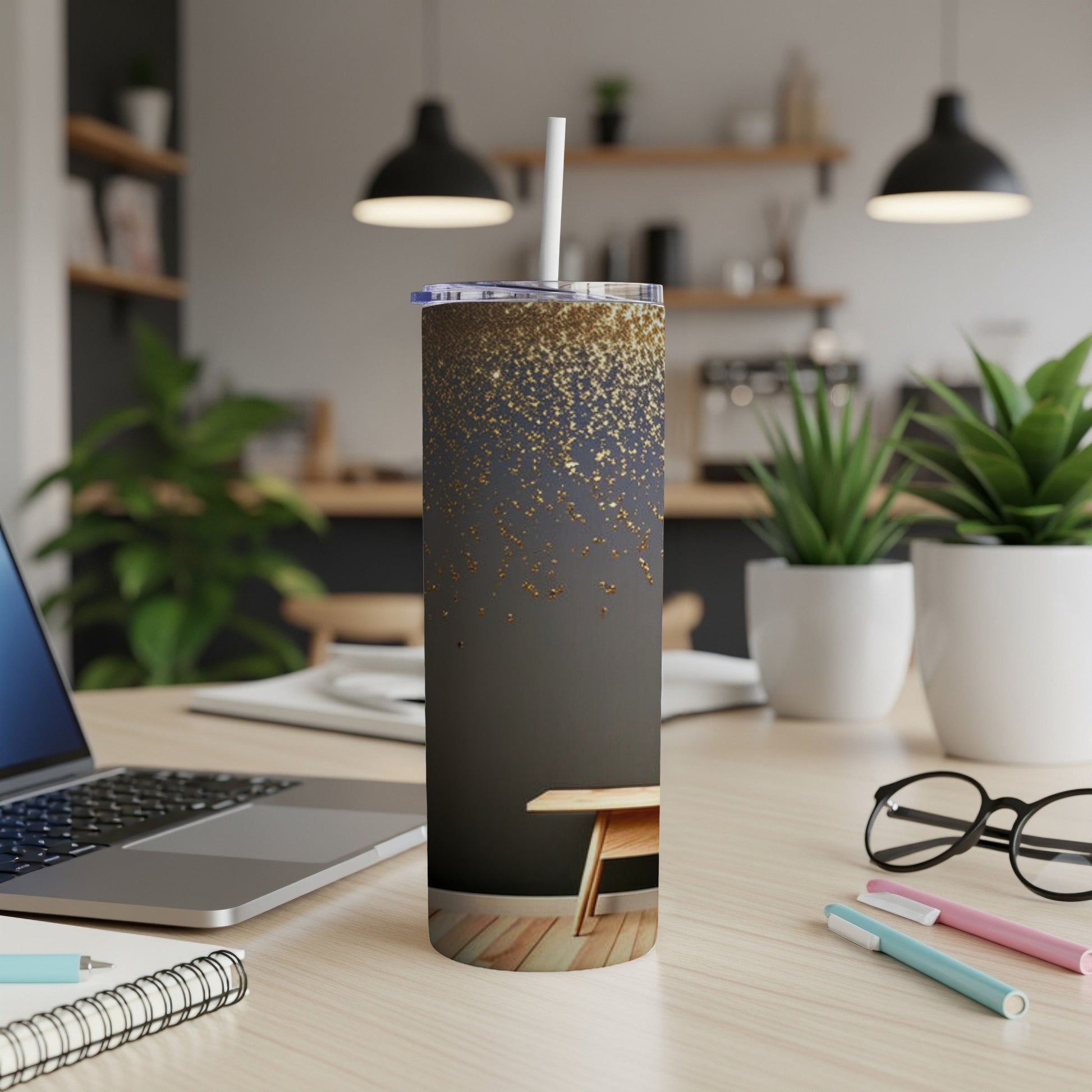 Sleek tumbler with gold glitter design on a dark background, on a desk.