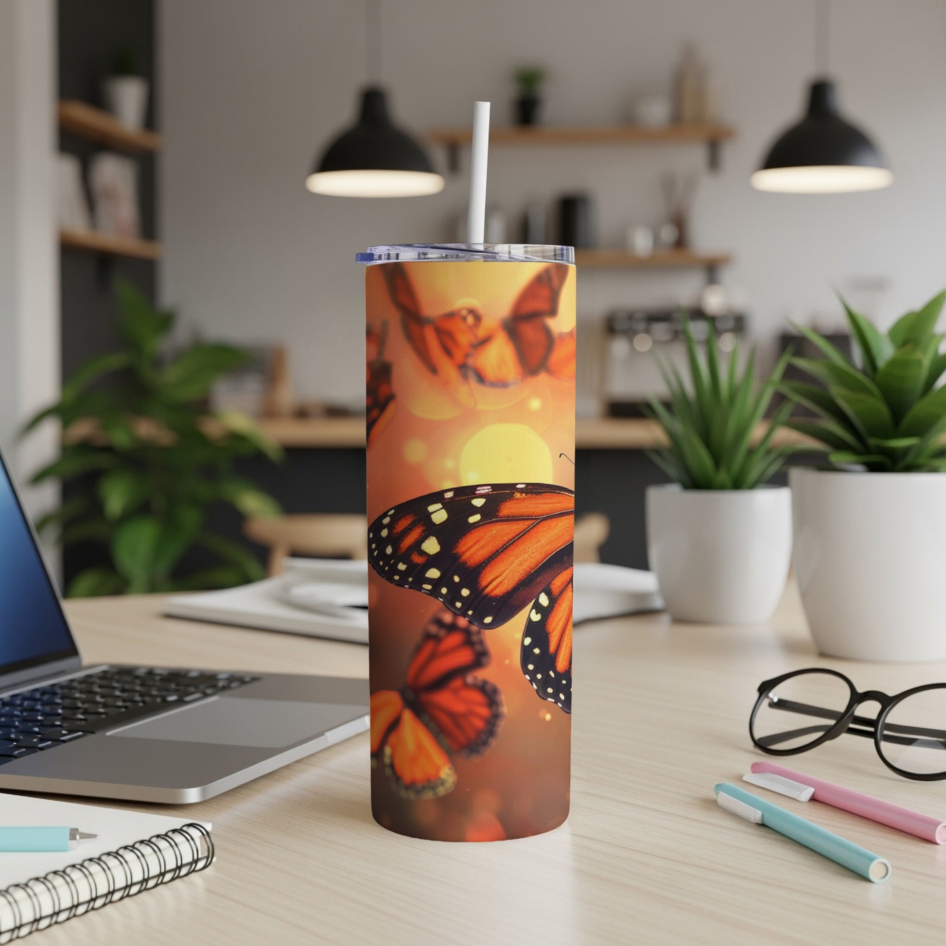 Orange monarch butterflies on a sunset-orange tumbler with a white straw.