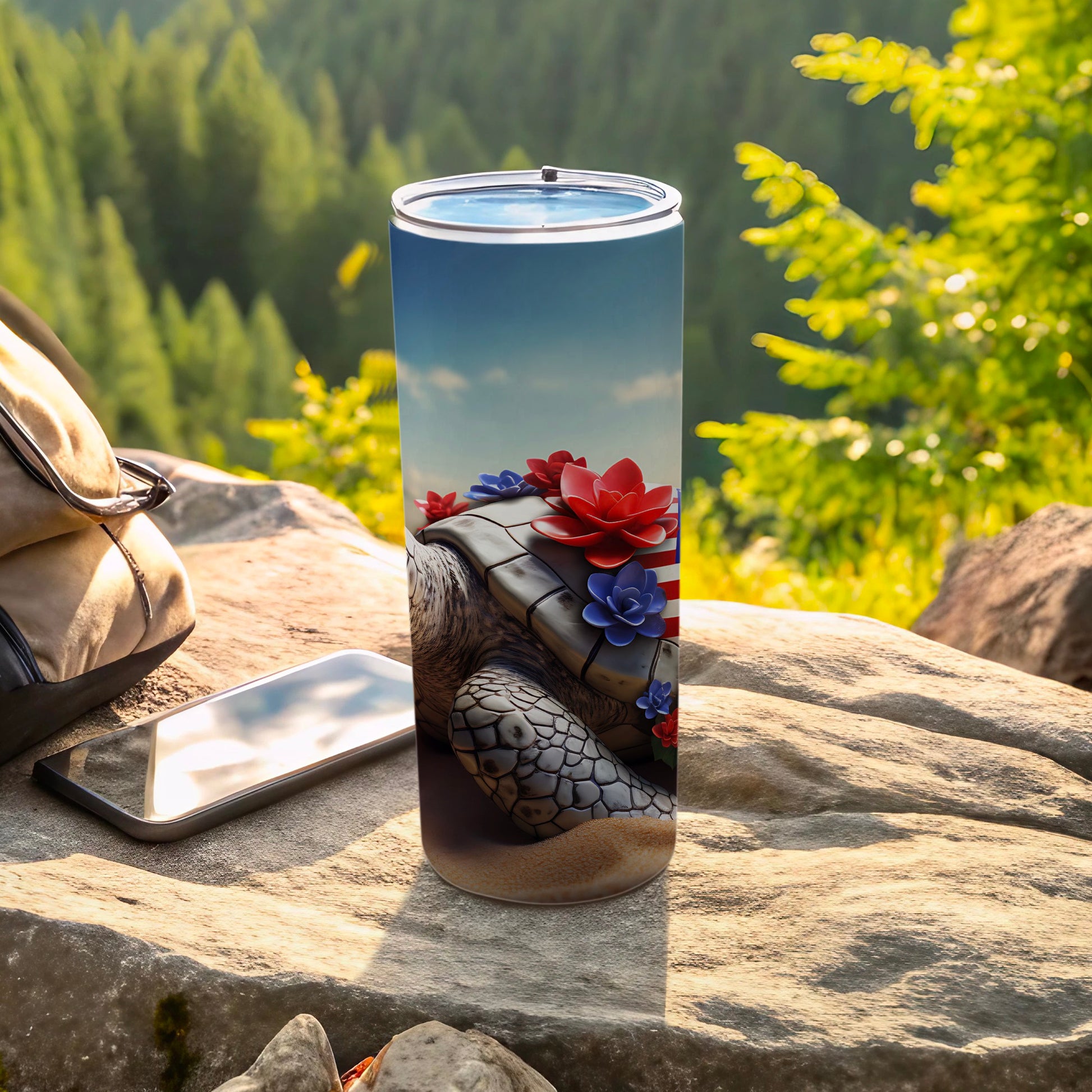 Turtle tumbler with floral and flag accents, next to phone and bag.