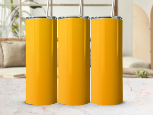Three plain yellow tumblers with straws stand on a marble surface.