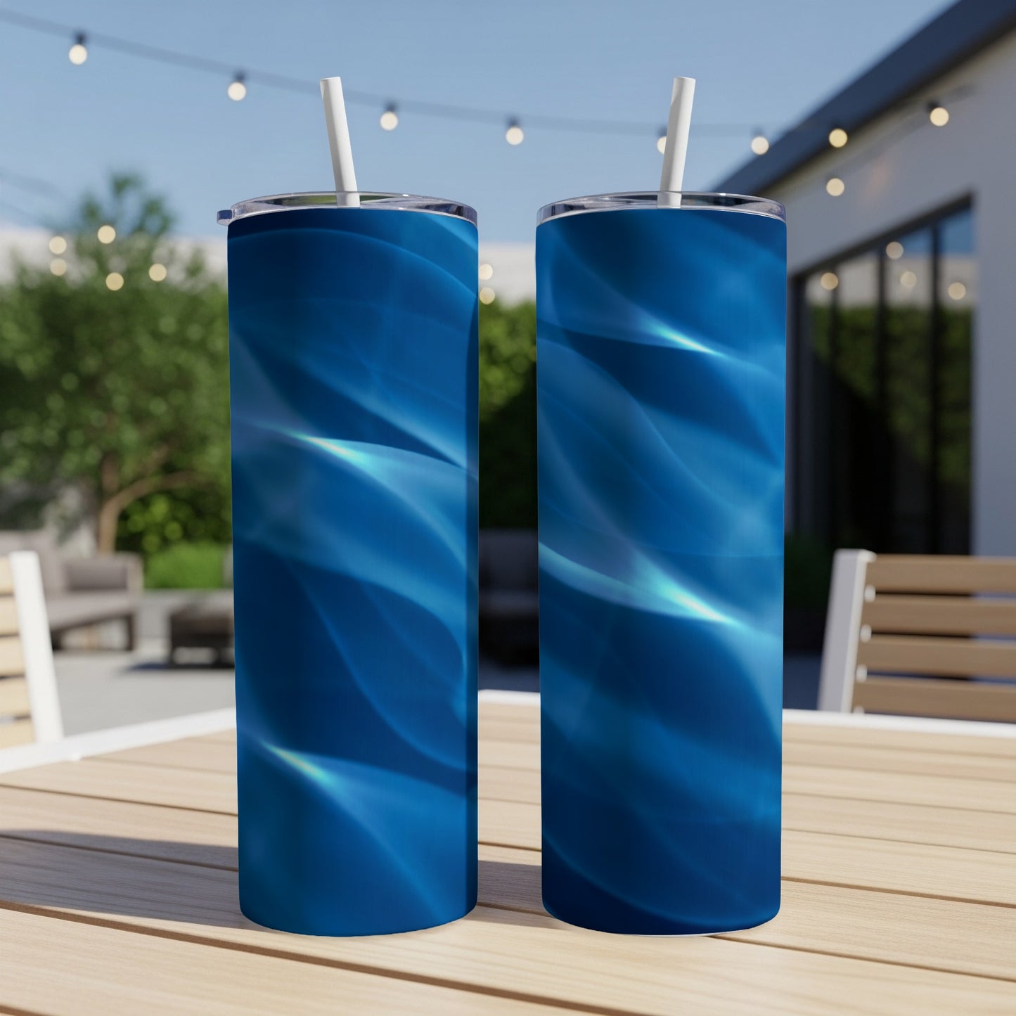 Two blue abstract wave pattern tumblers with straws on a table.