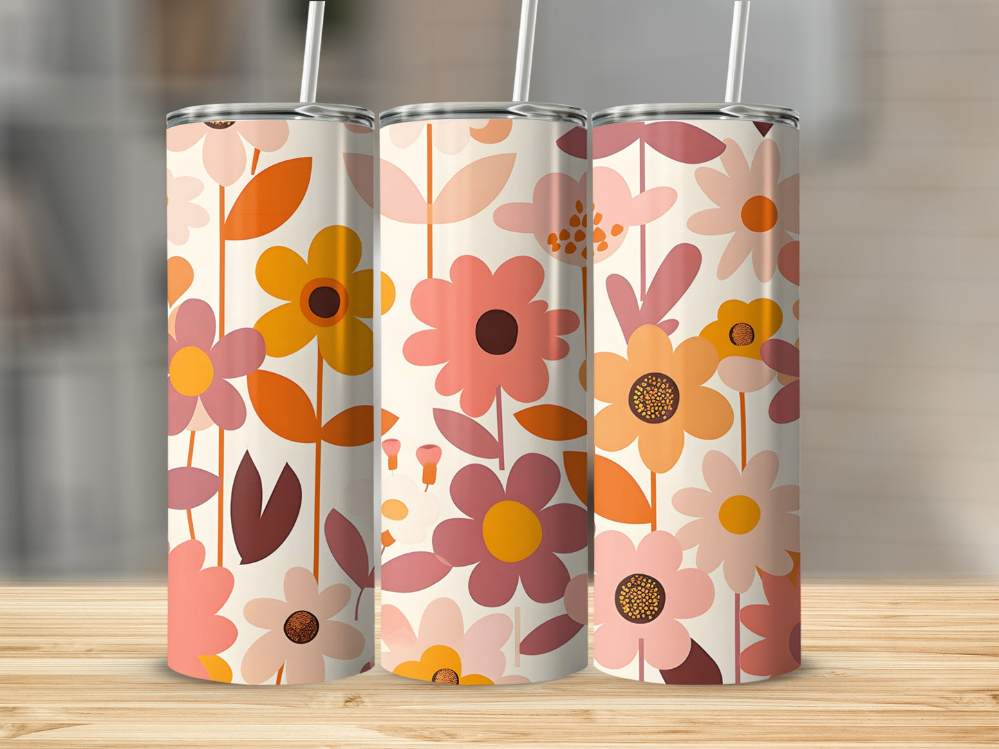 Three floral print tumblers with straws on a wooden surface.