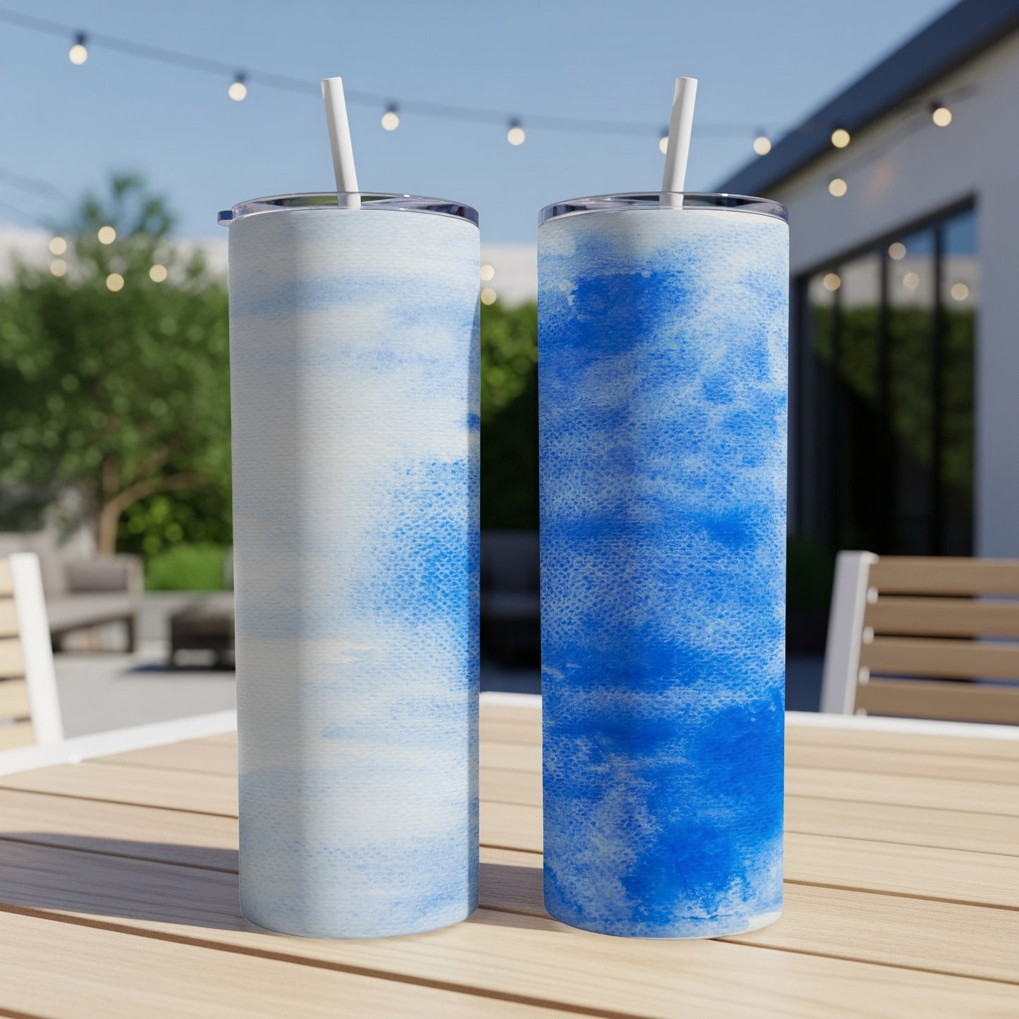 Two blue watercolor tumblers with straws on a wooden table.