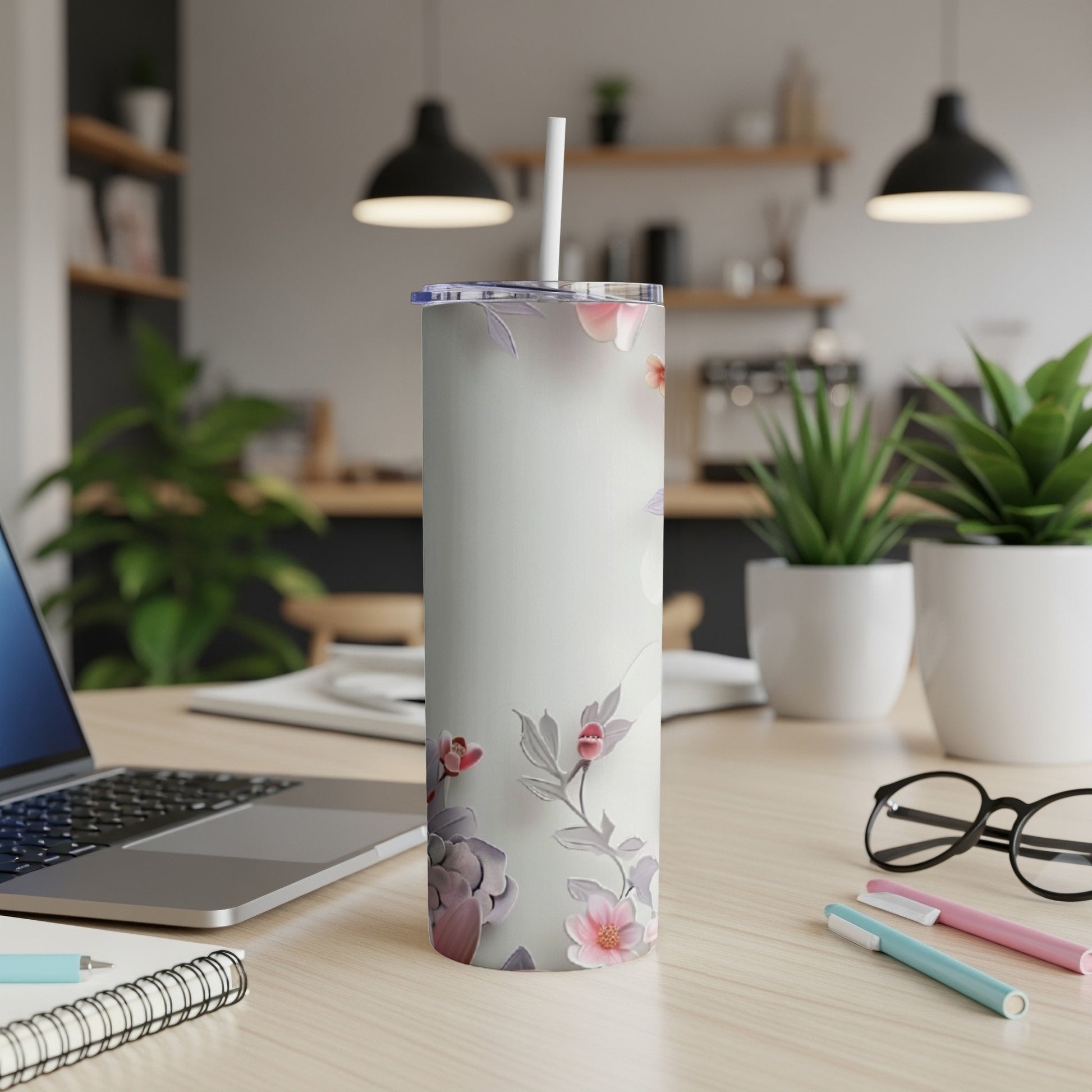 White tumbler with floral design on a desk next to a laptop.