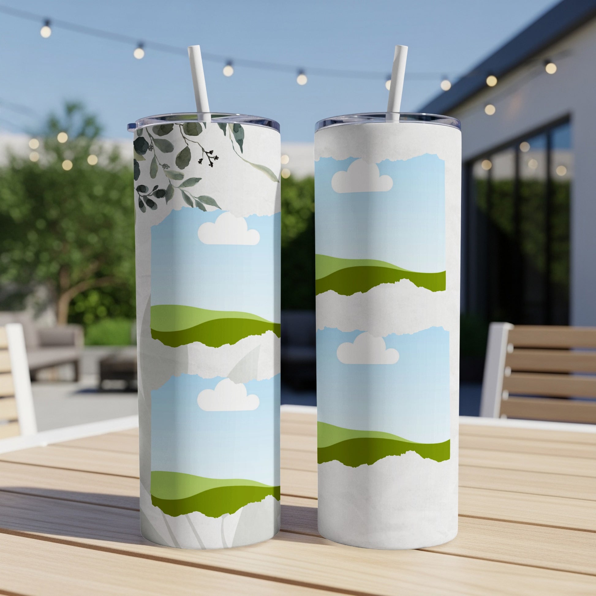 Two skinny tumblers with sky, cloud, and green hill designs.