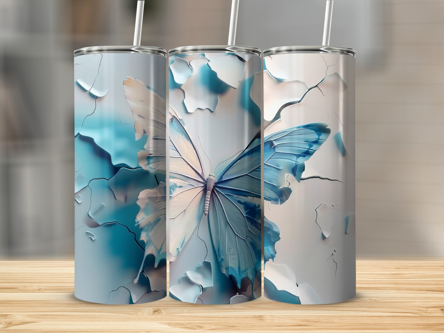 Three blue and white butterfly tumblers with straws on a wooden surface.