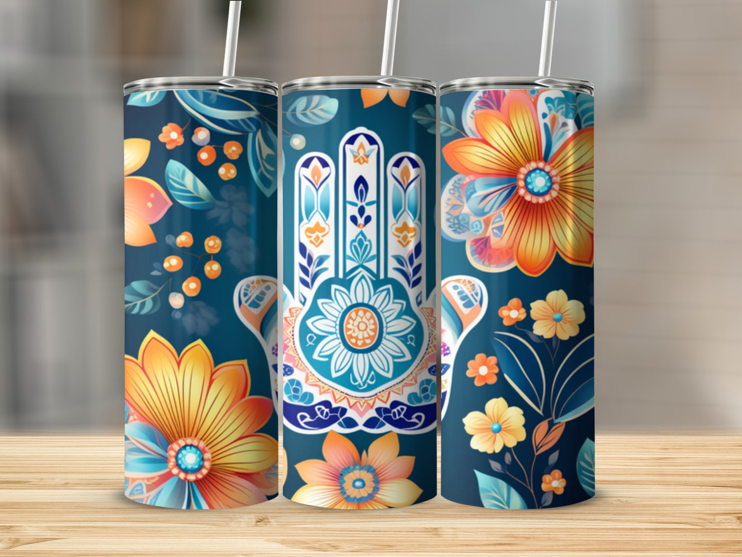 Three tumblers with floral and hamsa hand designs on a wooden surface.