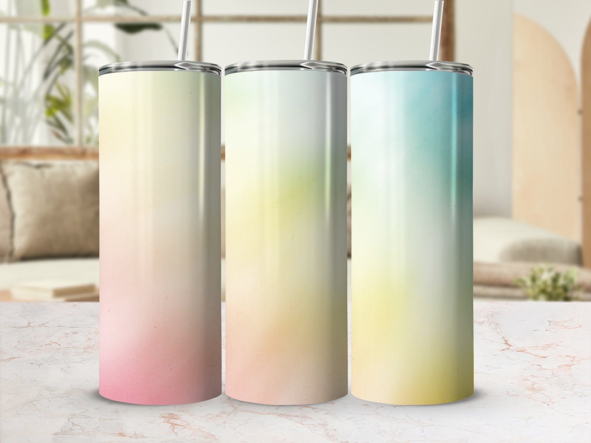 Three gradient tumblers with straws sit on a marble surface.