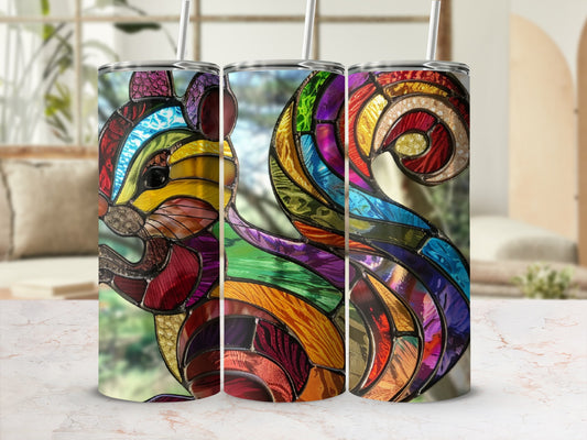 Stained glass squirrel tumbler with straw on a marble surface.