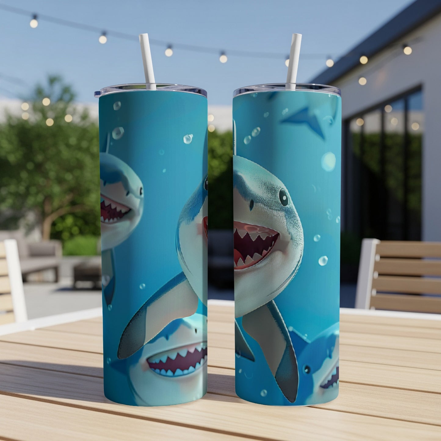 Two tumblers with smiling shark illustrations, on a table outdoors.