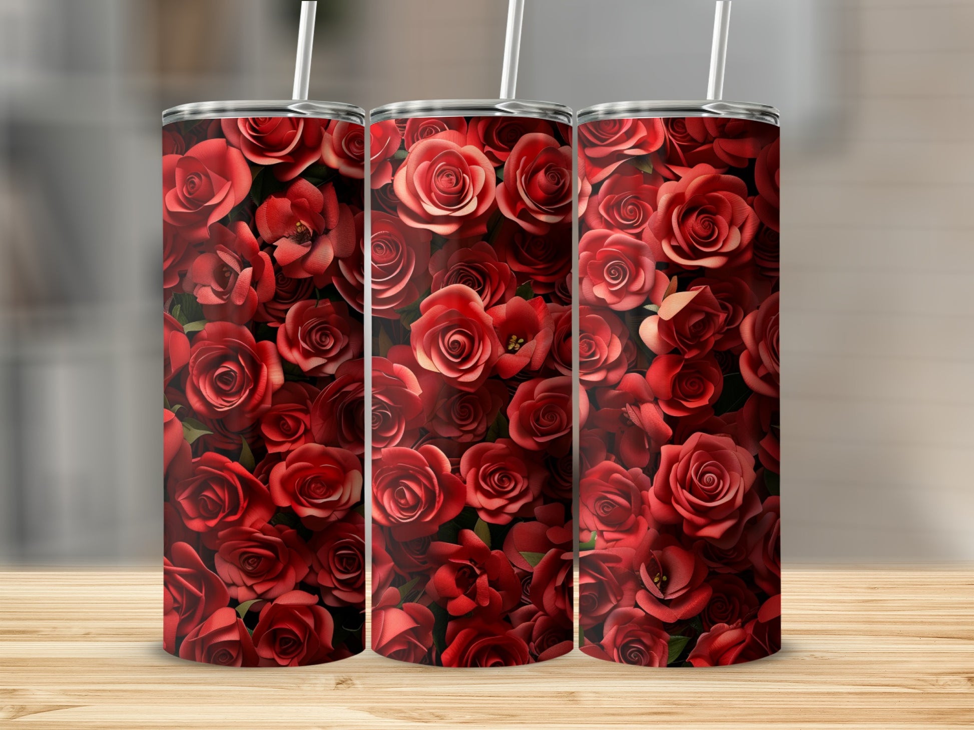 Three red rose tumblers with straws on a wooden surface.