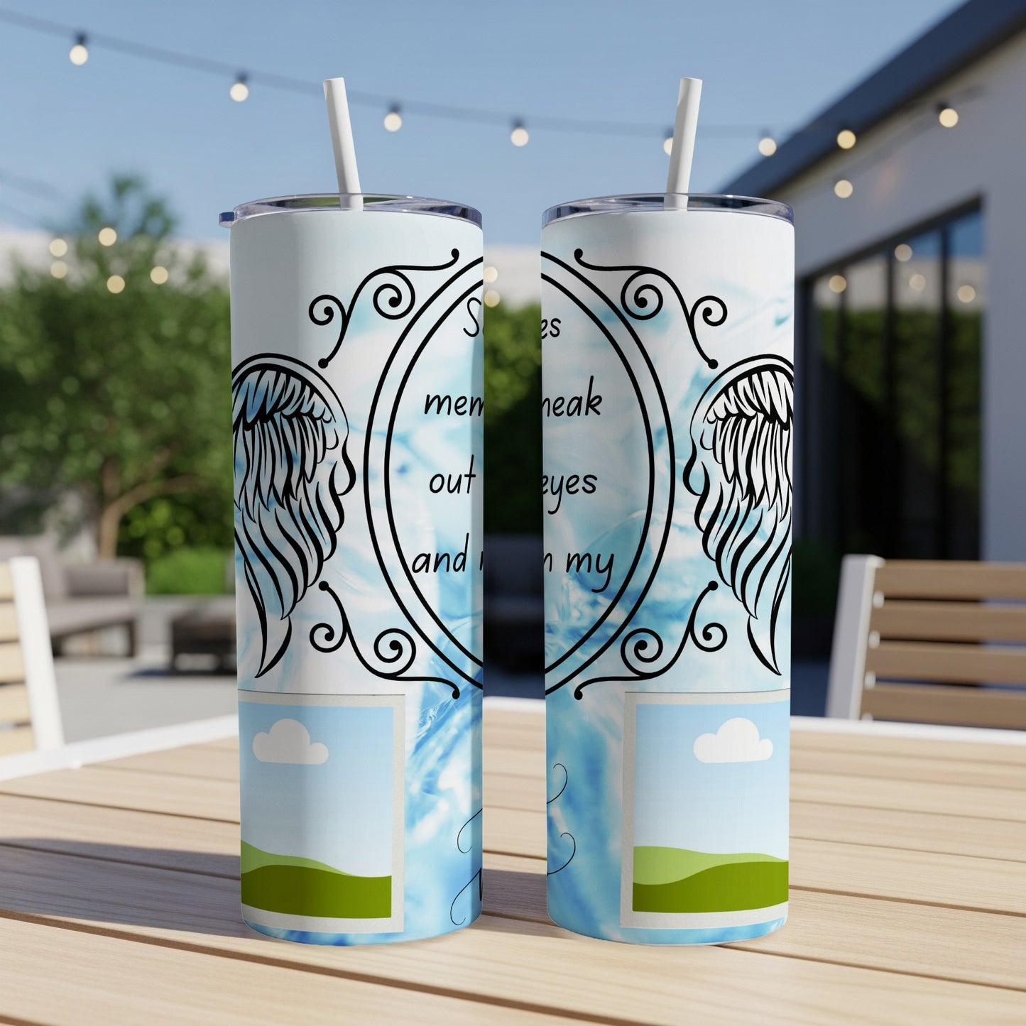 Two tumblers with angel wings and memorial text on a patio table.