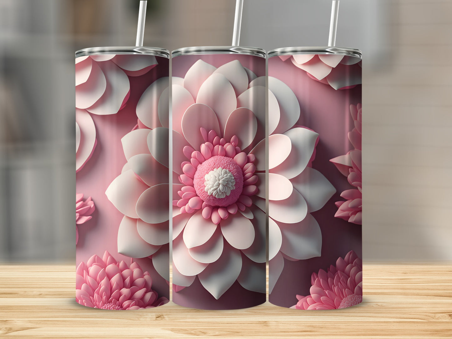 Three pink floral tumblers with straws on a wooden surface.
