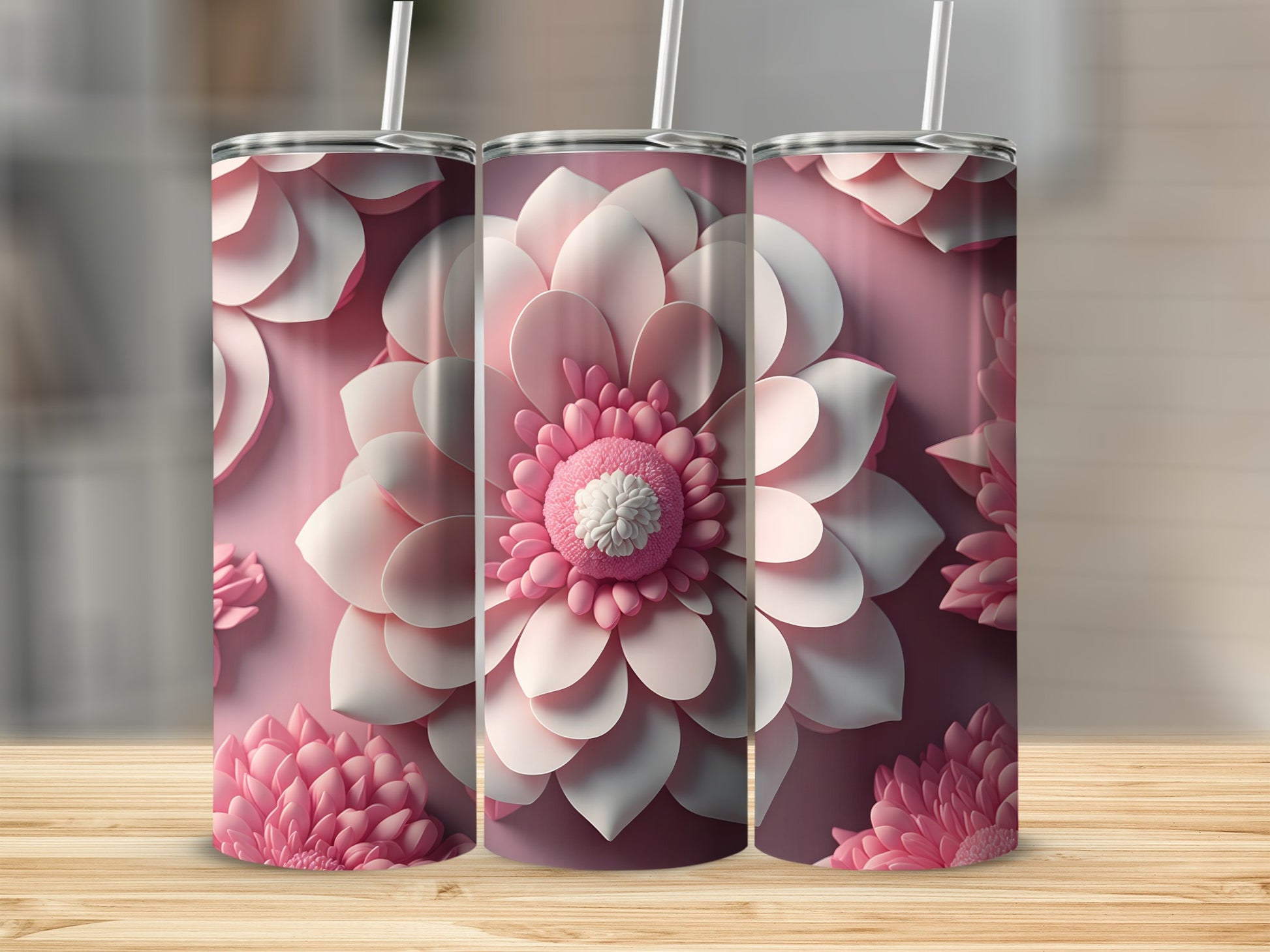 Three pink floral tumblers with straws on a wooden surface.
