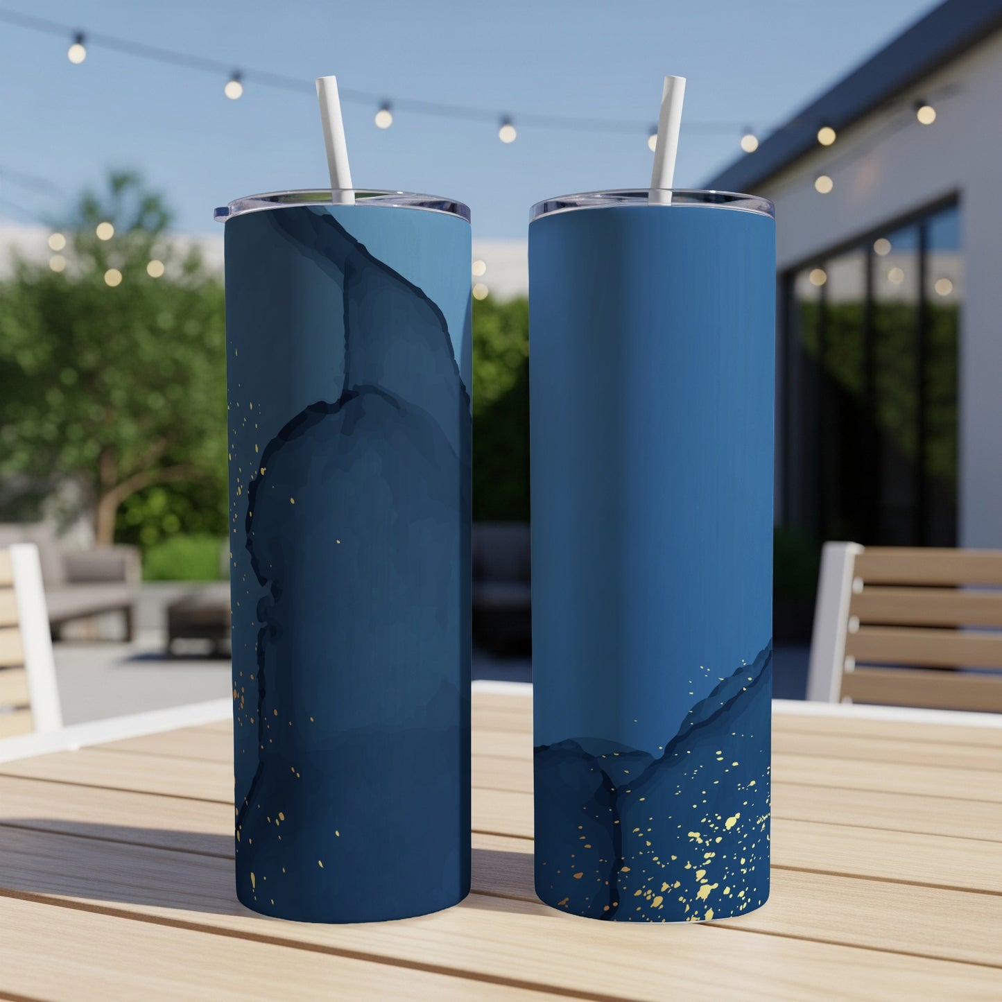 Two navy blue tumblers with gold speckle design on outdoor table.
