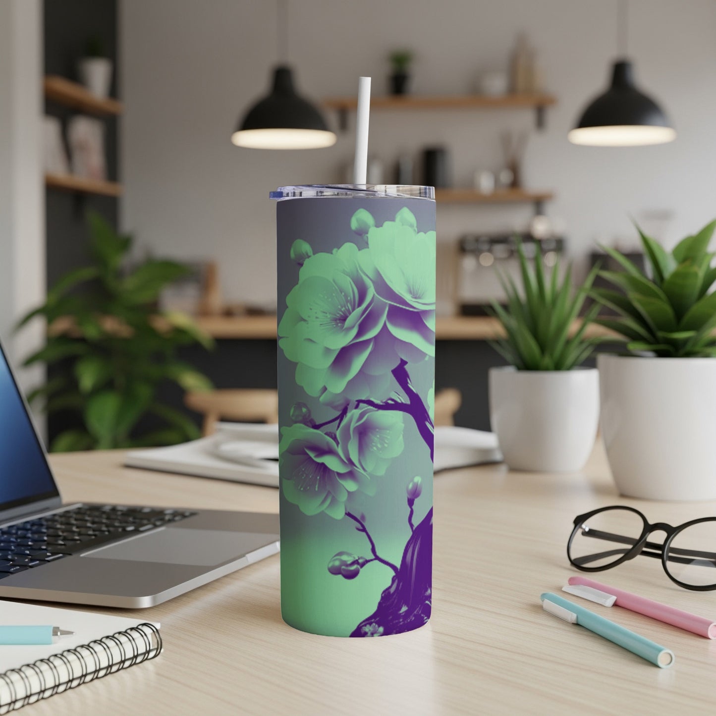 Purple and green floral tumbler with straw on desk.