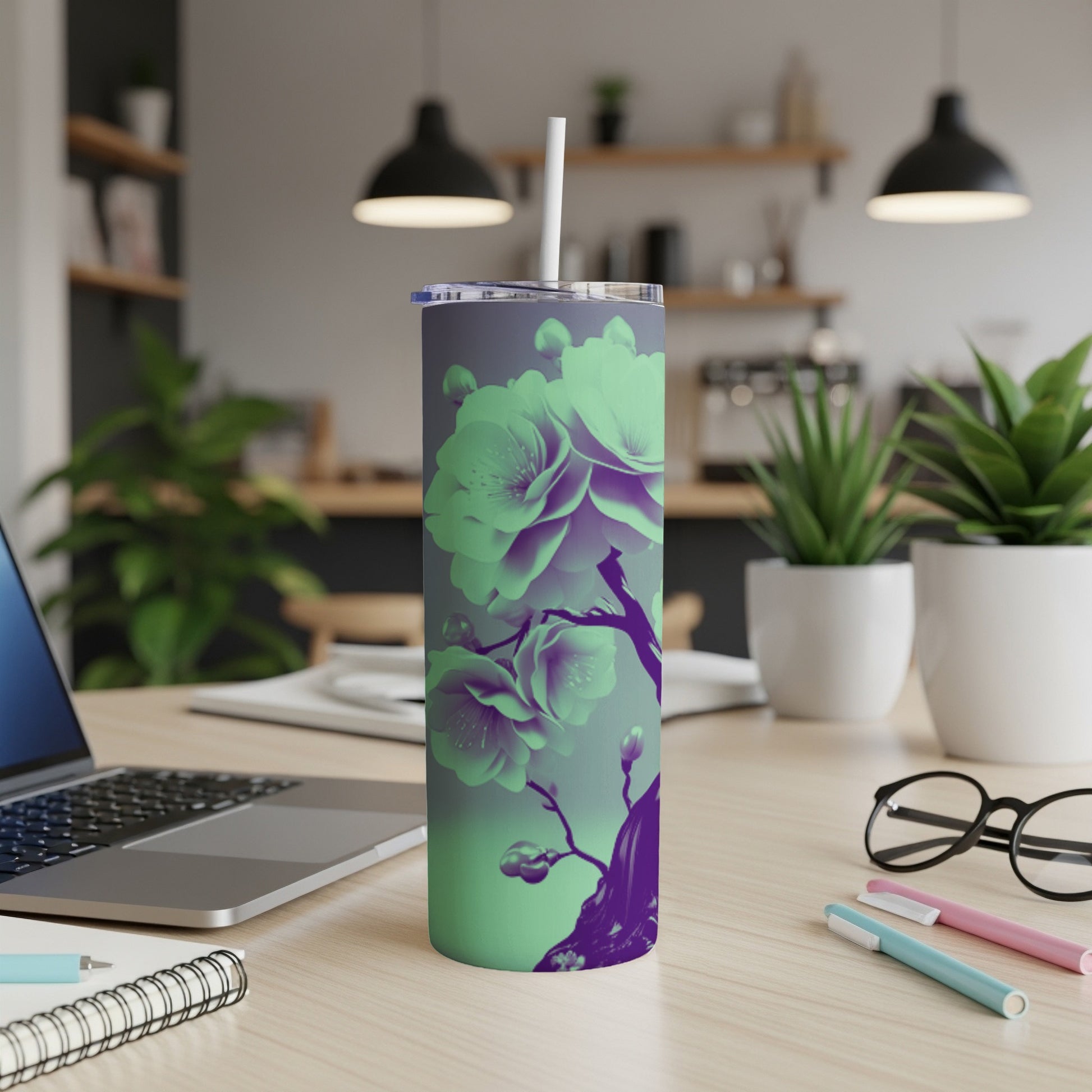 Purple and green floral tumbler with straw on desk.