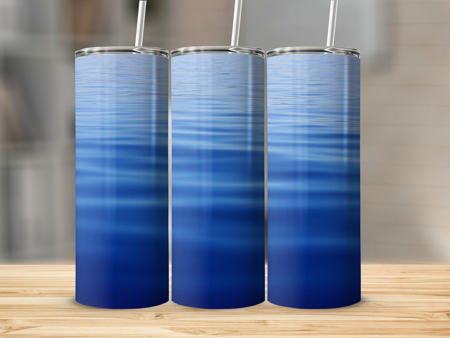 Three blue water ripple tumblers with straws on a wooden surface.