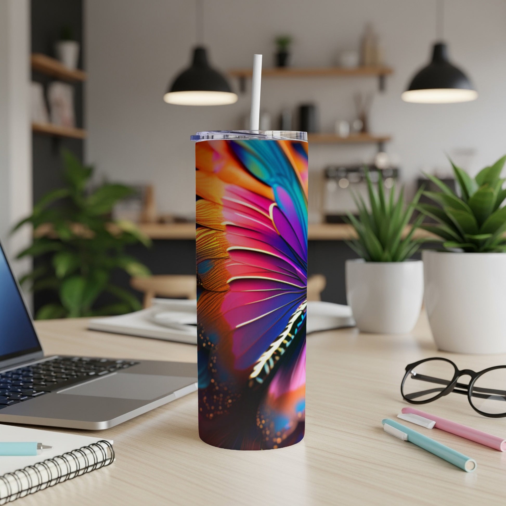 Colorful feather pattern on a tumbler with straw on a desk.