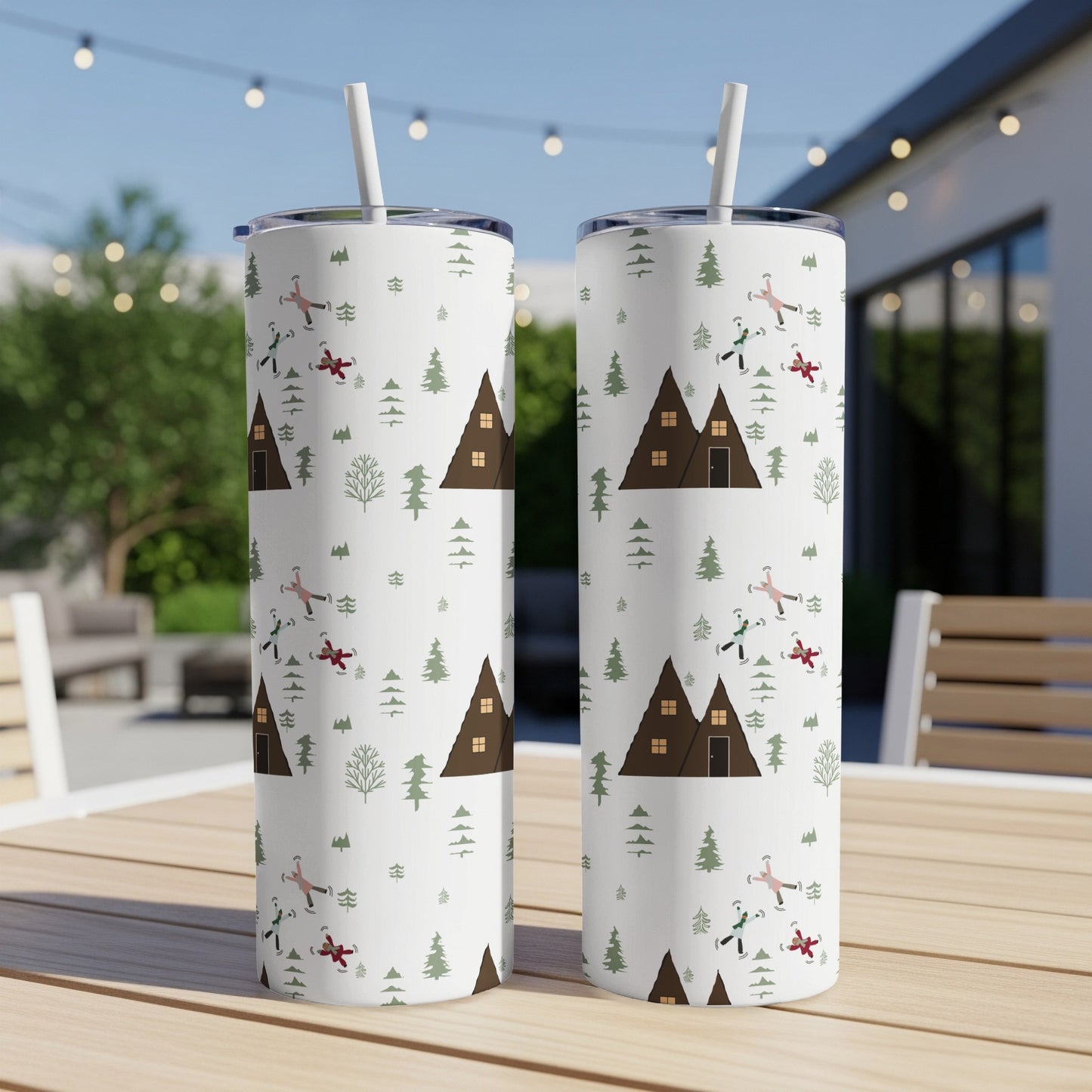 White tumblers with festive winter woodland pattern, houses, and people skiing.