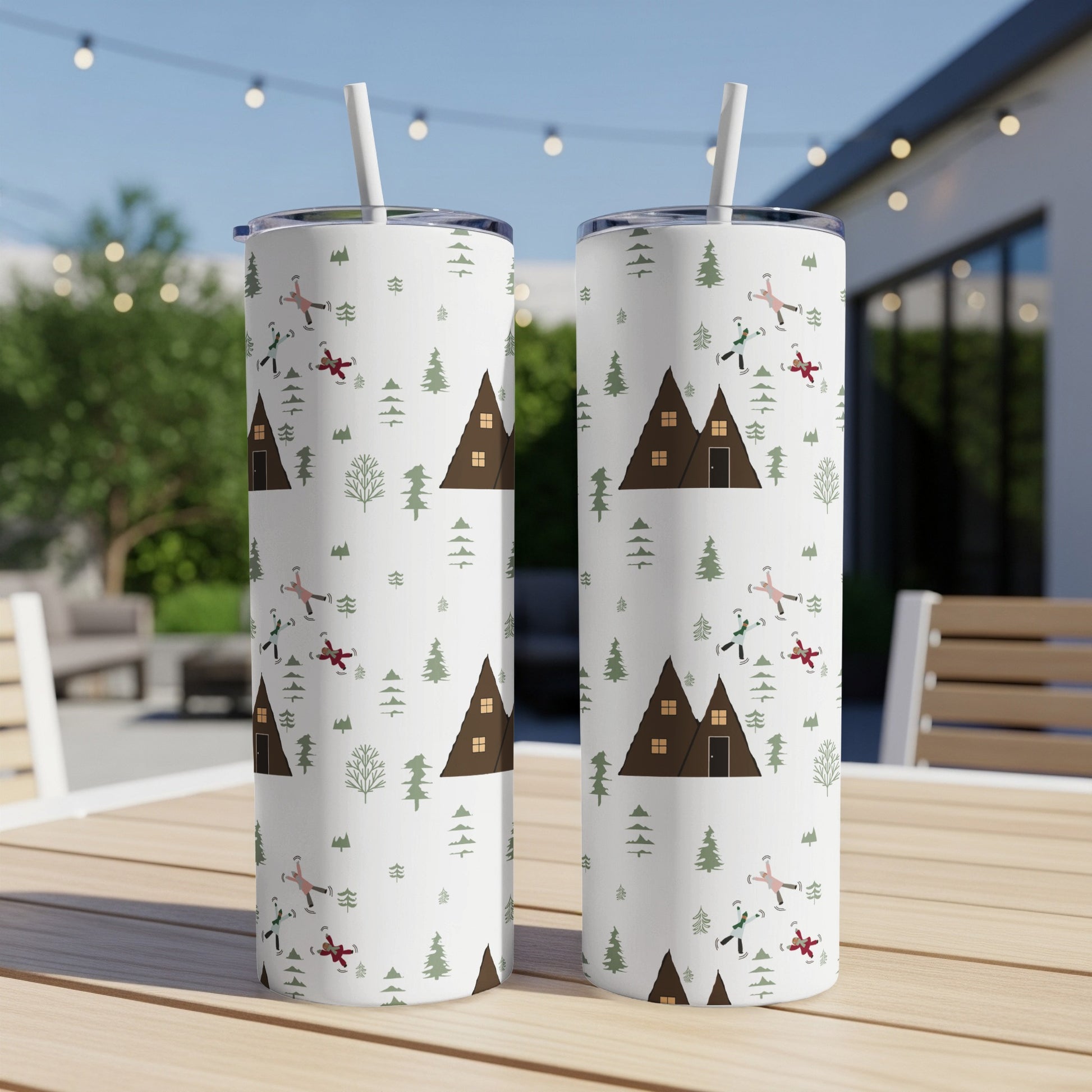White tumblers with festive winter woodland pattern, houses, and people skiing.