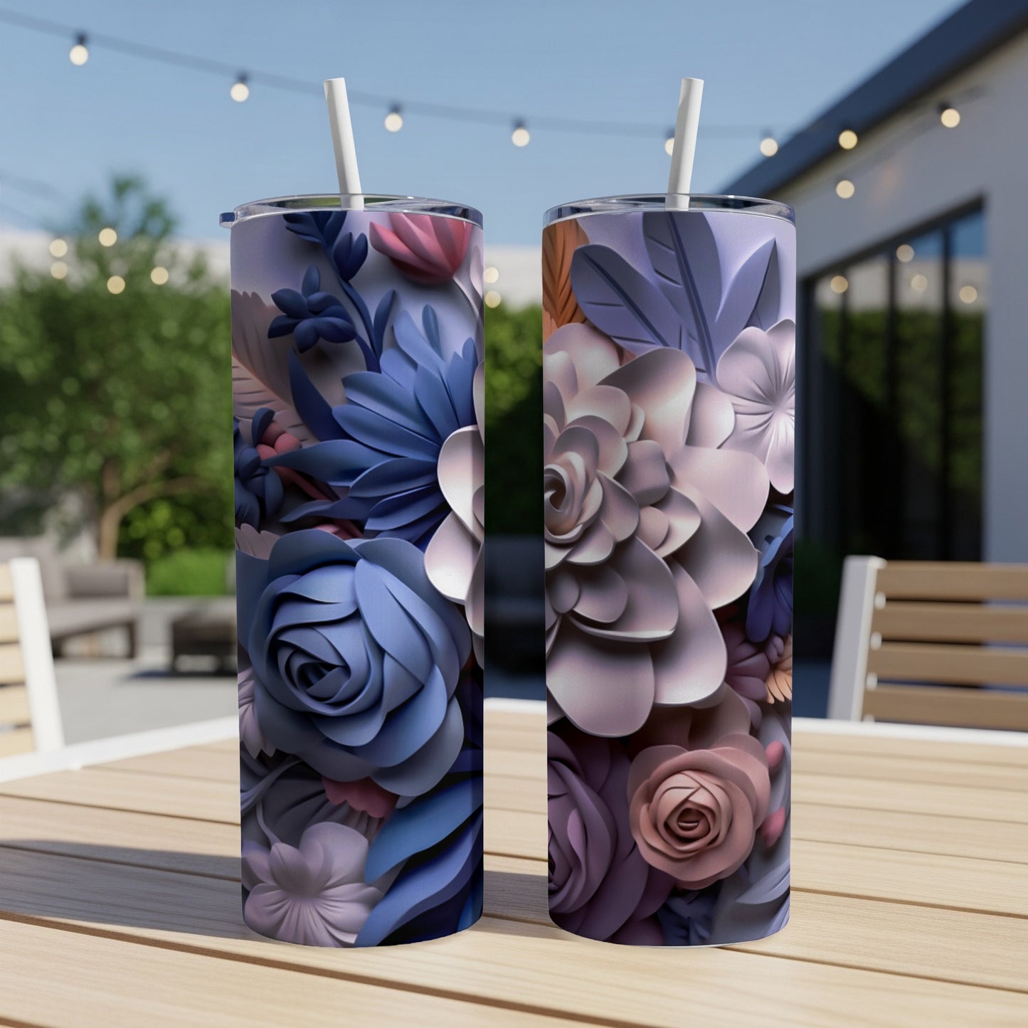 Two tumblers with floral designs sit on a wooden table outdoors.