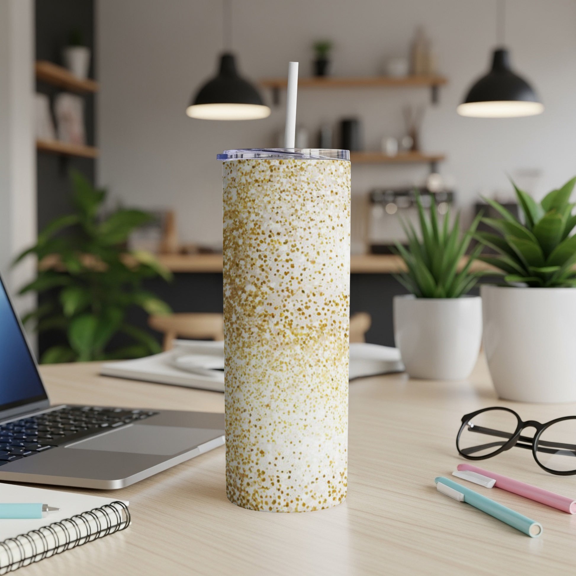 Gold glitter tumbler with straw on a desk next to a laptop.