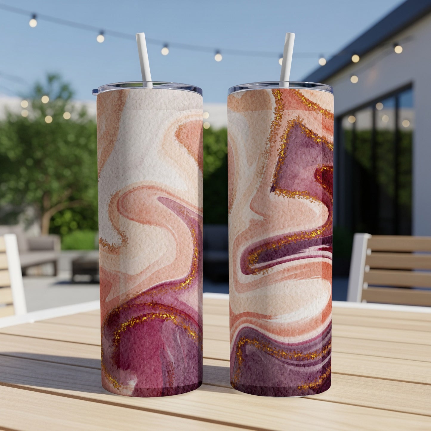 Two tall tumblers with marbled pink, peach, and gold patterns on a wooden table.