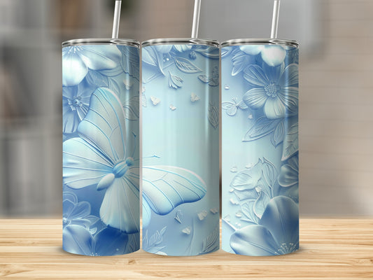 Three pastel blue tumblers with embossed butterflies and flowers on a wooden surface.