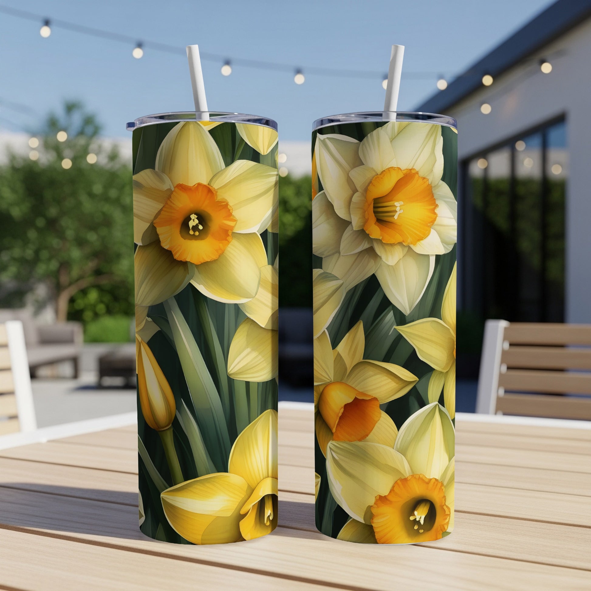 Two tumblers with a yellow daffodil floral pattern on an outdoor table.