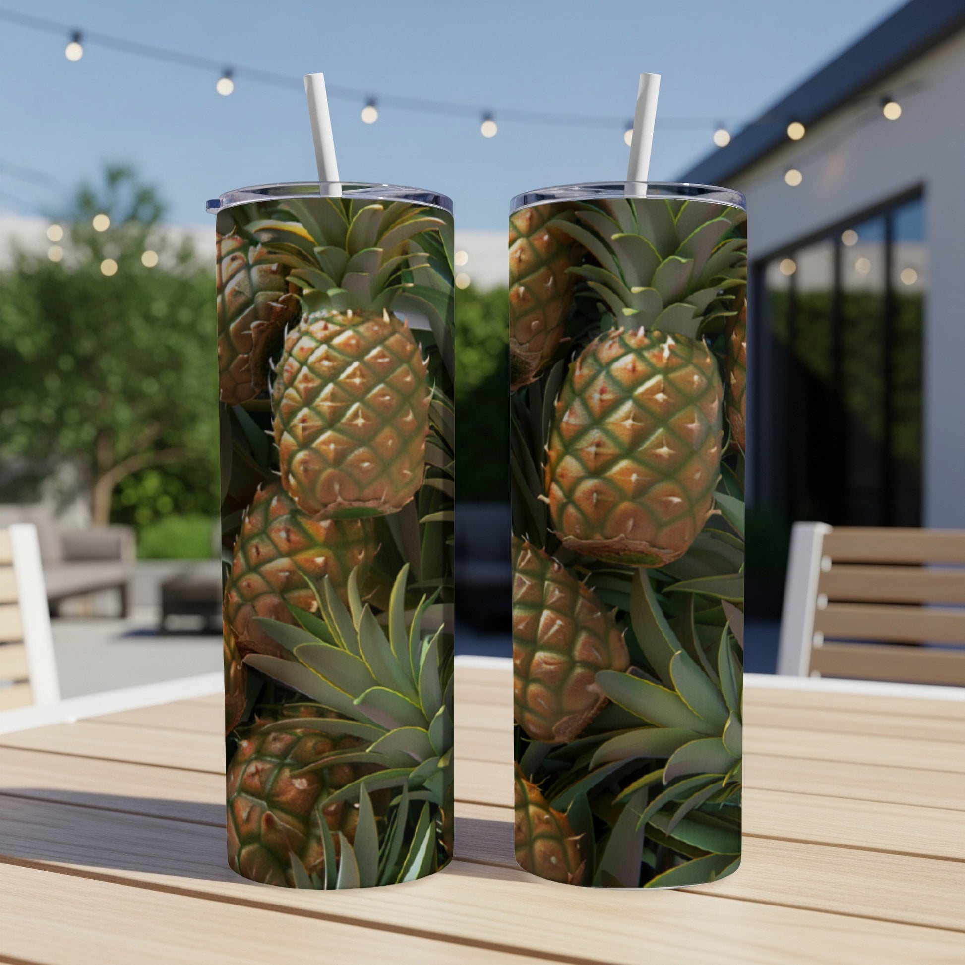 Two tumblers with pineapple design sit on a table outdoors.