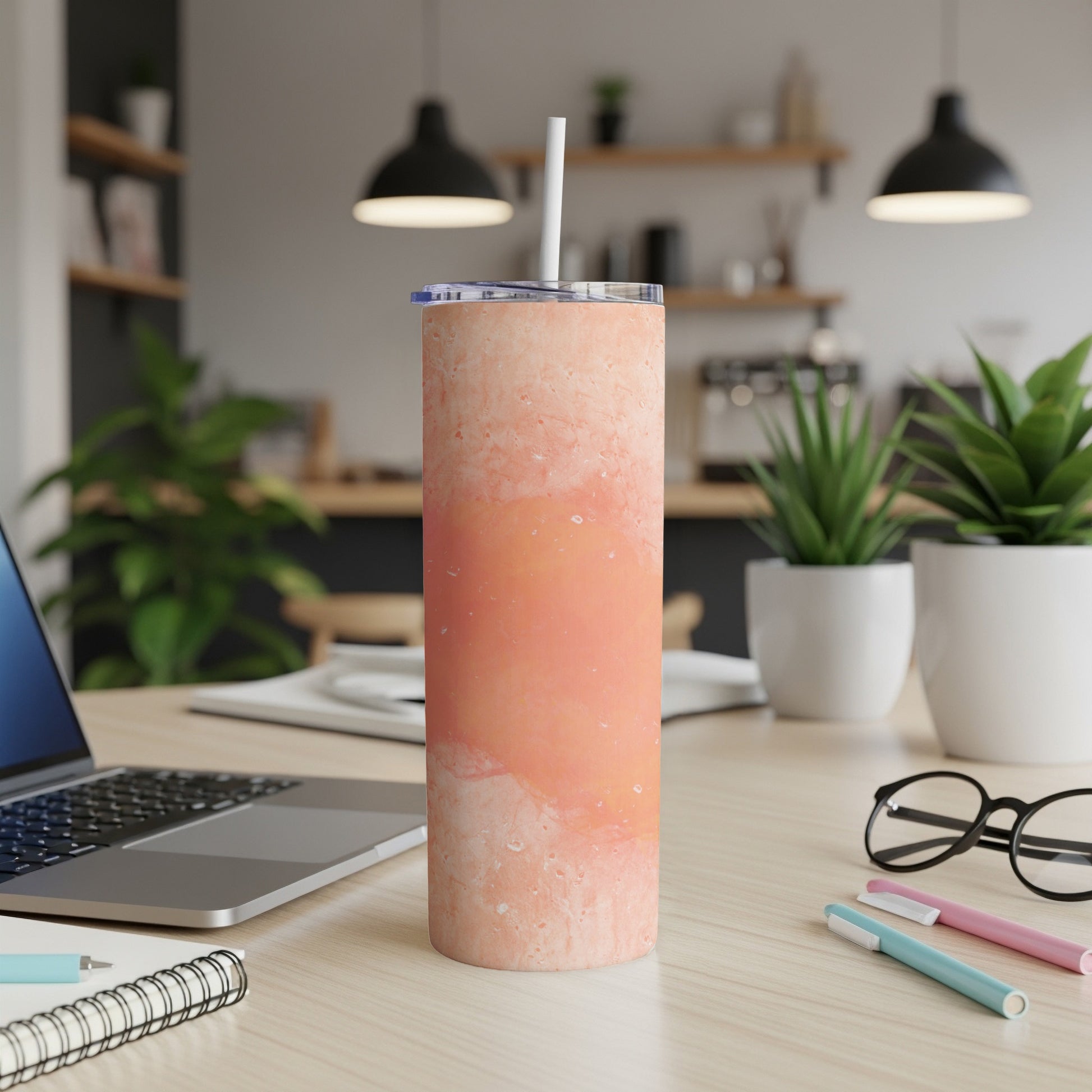 Marble-patterned insulated tumbler with straw on a desk.