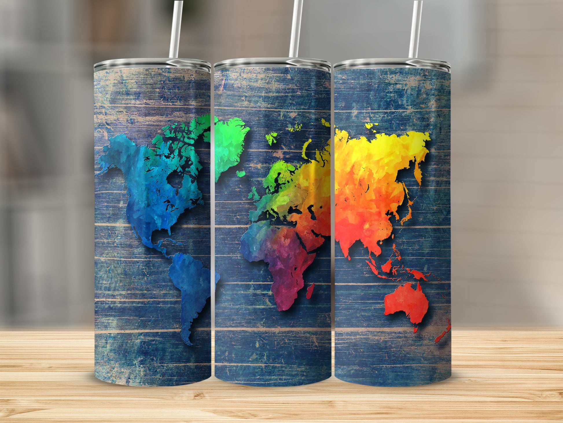 Three tumblers with colorful world maps on a distressed blue wood background.