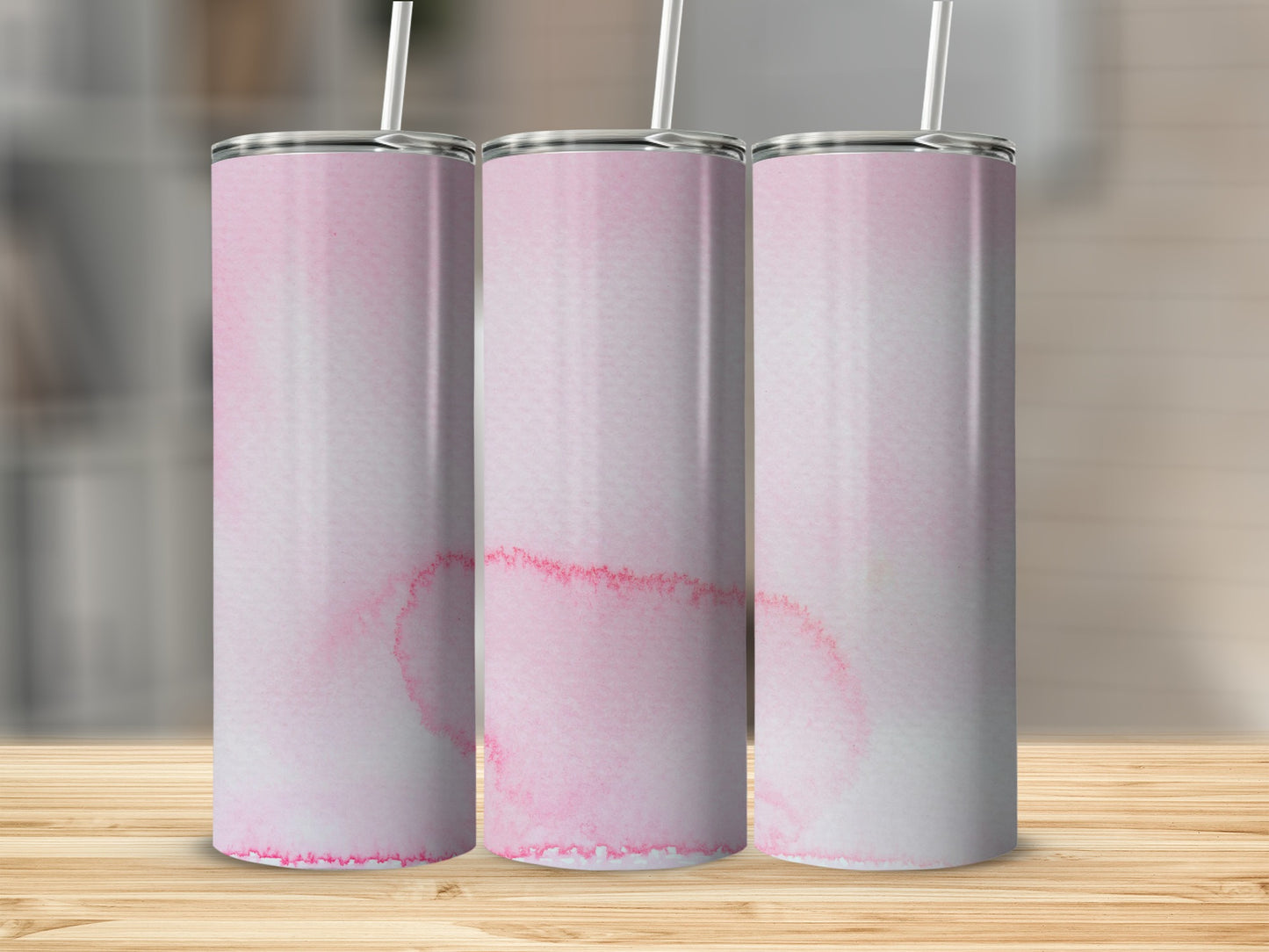 Three pink watercolor tumblers with straws on a wooden surface.