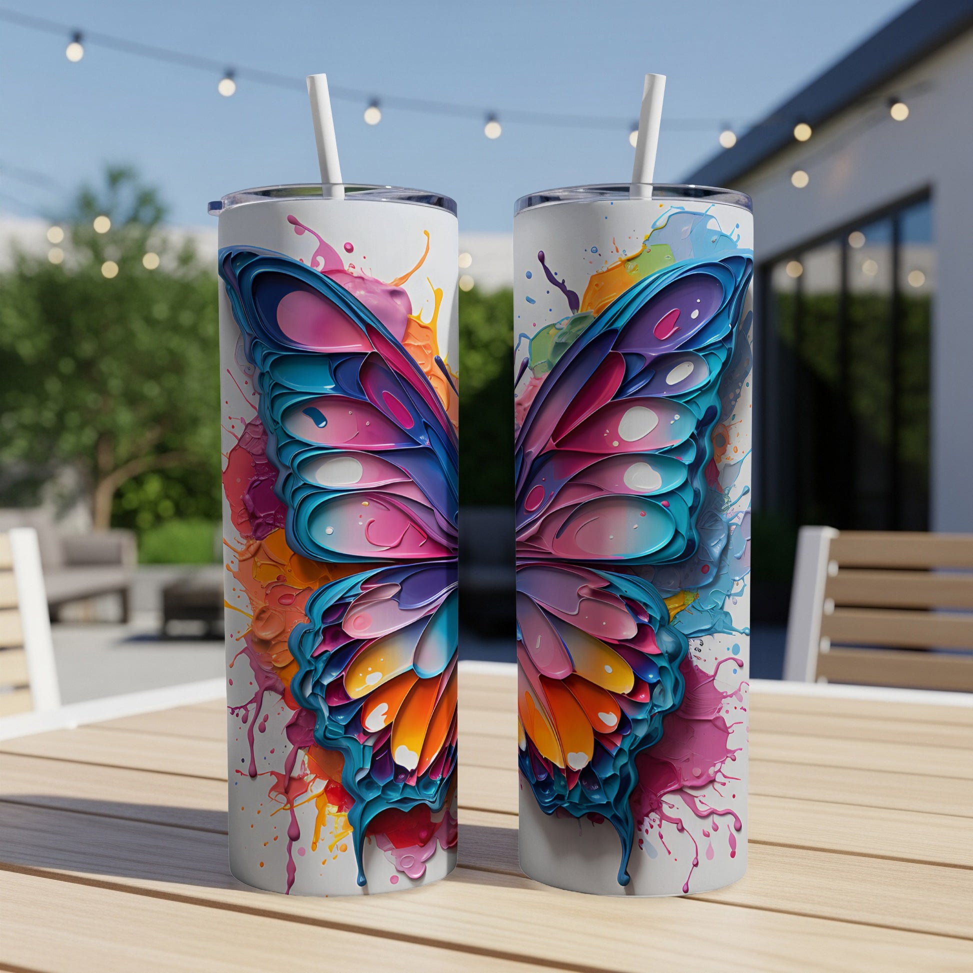 Two colorful butterfly wing tumblers with straws on a table.