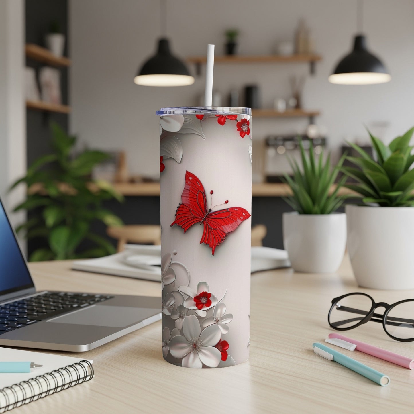 White tumbler with red butterfly and floral design, straw inserted.