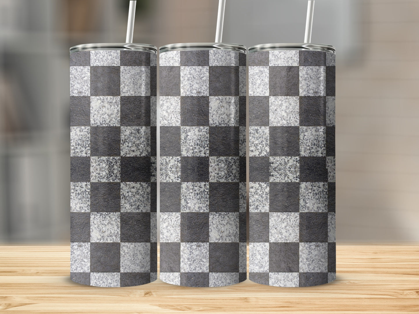 Three tumblers with a black and white checkerboard pattern and white straws.