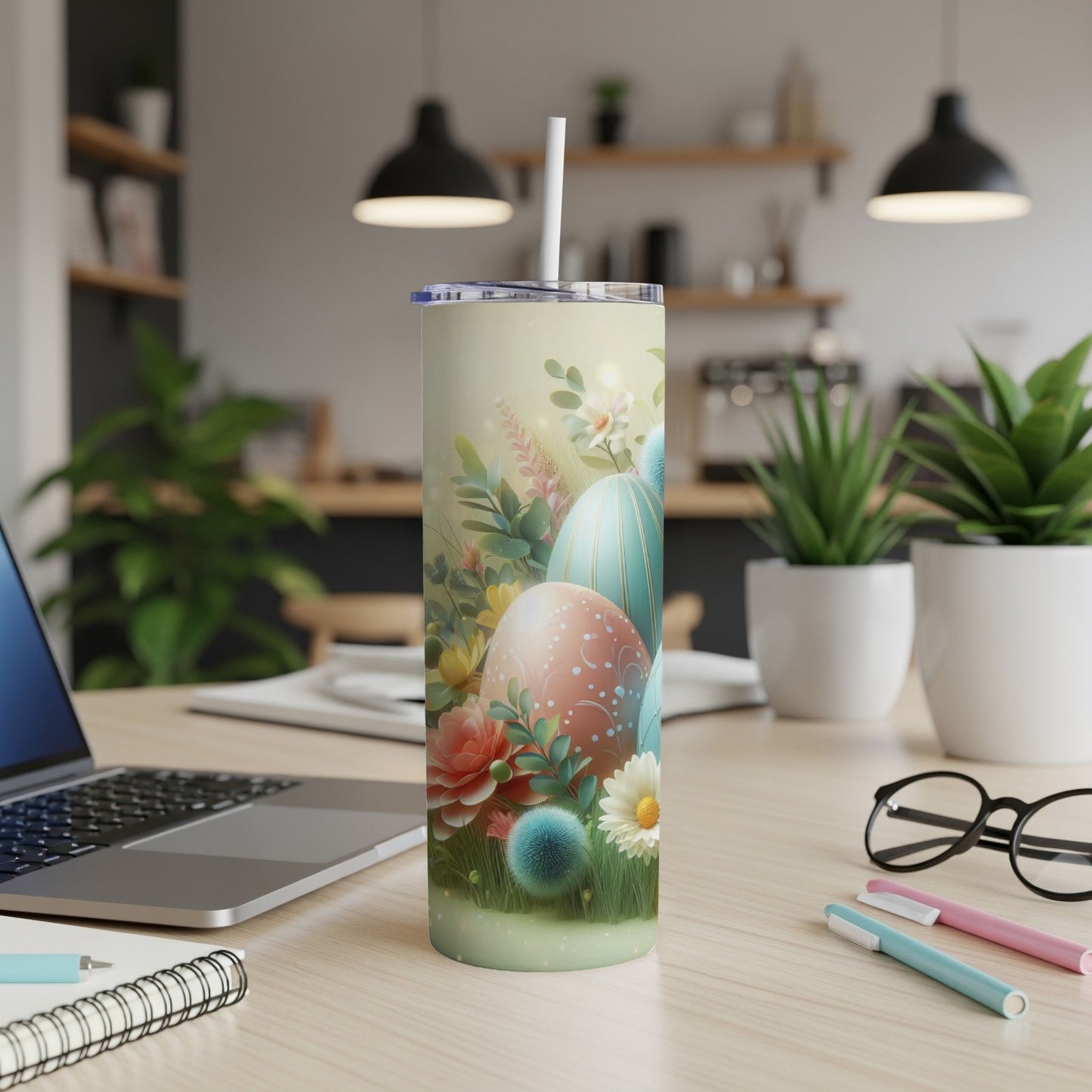 Easter egg design tumbler with flowers and greenery on a desk.