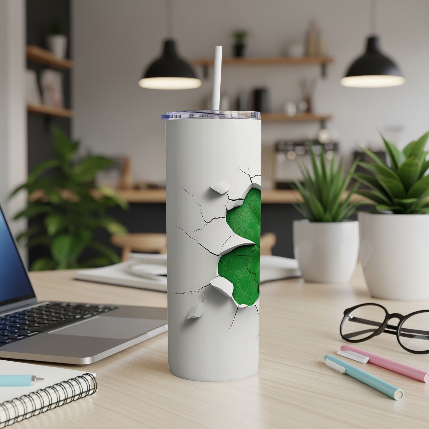 White tumbler with cracked green pattern, straw, on desk with laptop.